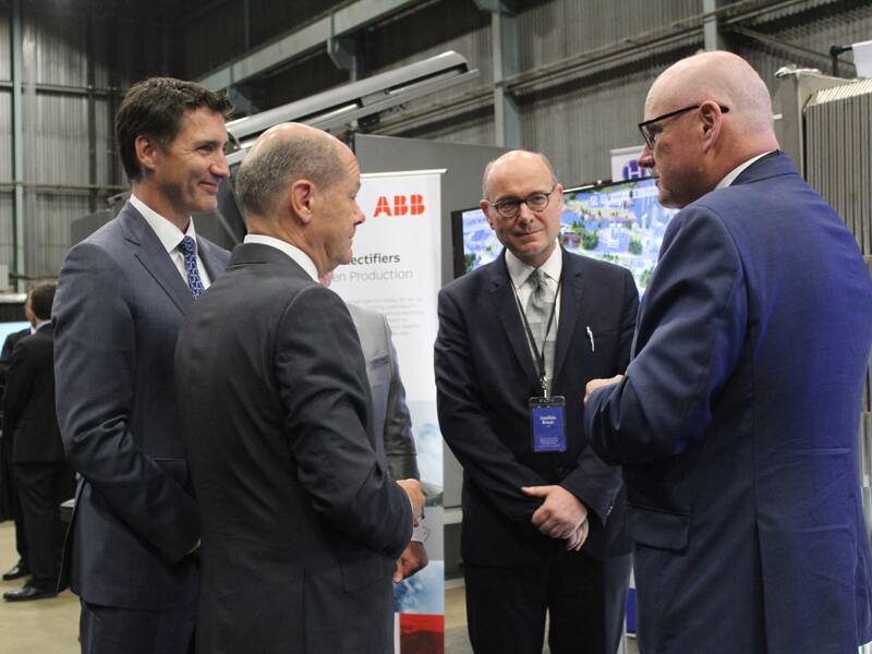 Justin Trudeau, Olaf Scholz, Joachim Braun, and Andrew Stuart stand in a circle at the German-Canadian Atlantic Renewable Hydrogen Expo in Stephenville, Newfoundland Aug. 23, 2022.